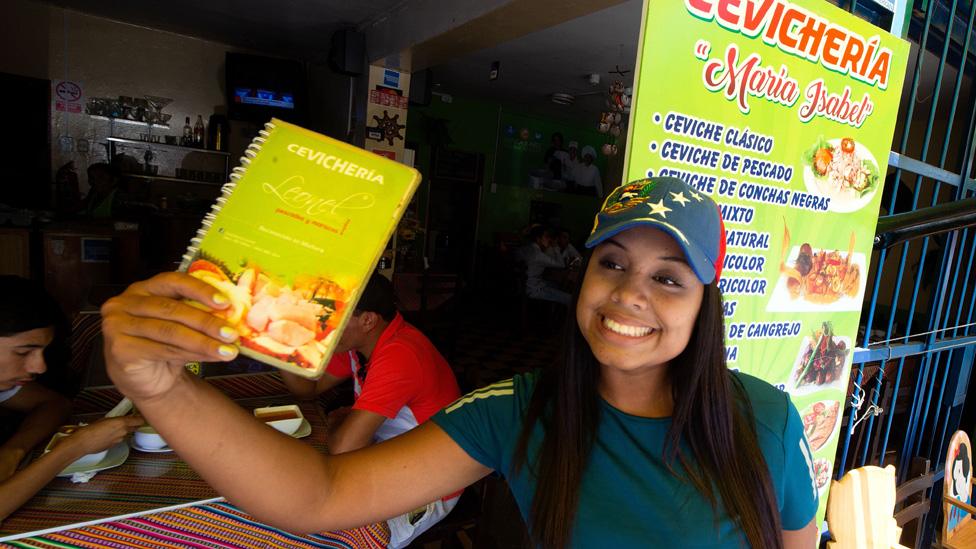 Venezuelan Liriannys Antoima calls passers-by into a restaurant where she works as a waitress in Lima on April 4, 2019.