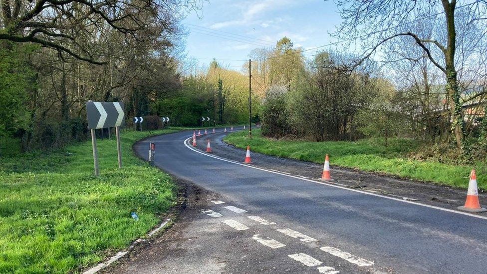 traffic cones alongside a damaged road