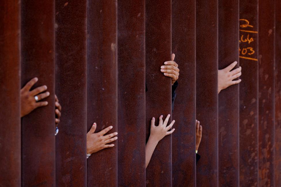 Migrants wait for some food from an aid worker after gathering between the primary and secondary border fences between Mexico and the United States as they await processing by U.S immigration in San Diego, USA. September 12, 2023.