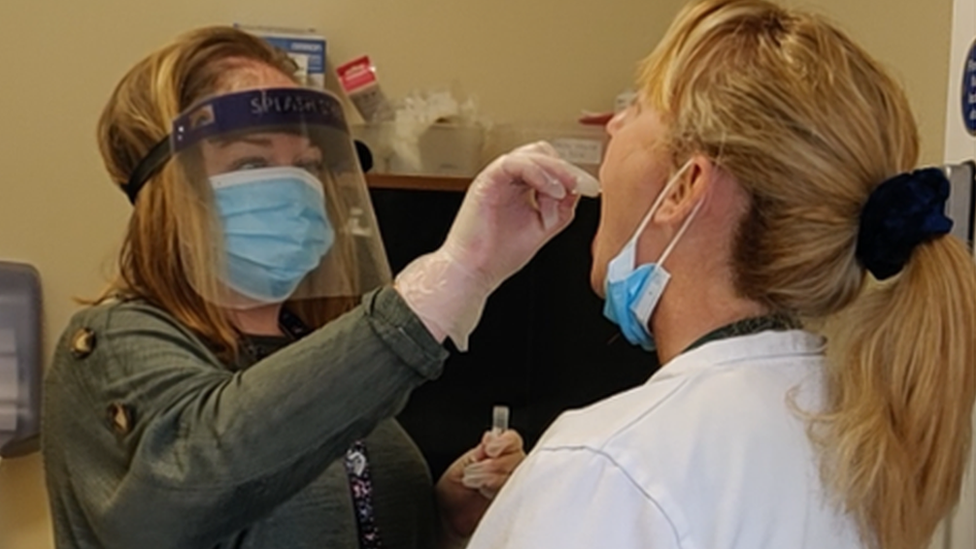 A care worker performs a covid test on a colleague