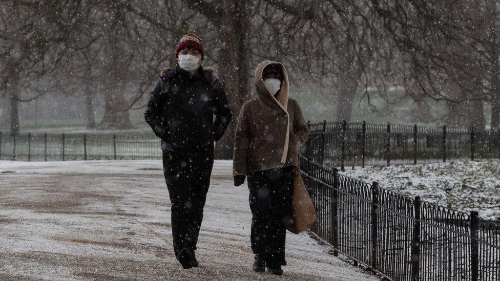 People walk in a snowy park in London