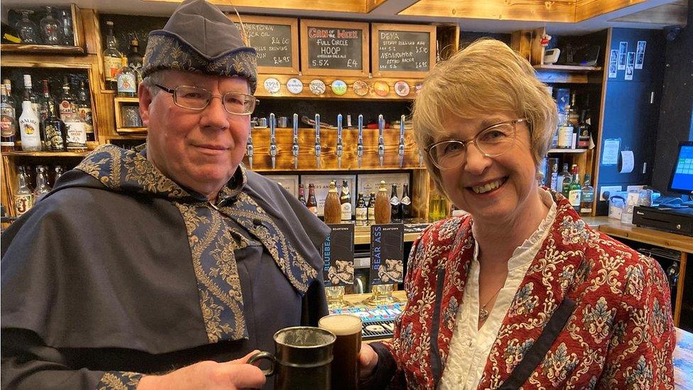 Ale taster and councillor holding up glasses of ale