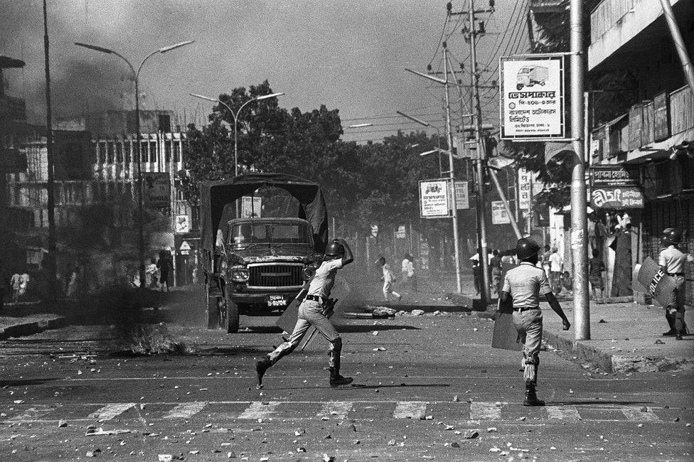 People throwing stones in the street towards police carrying shields