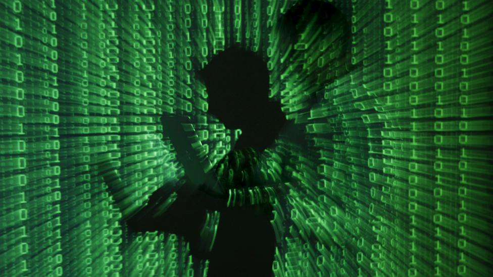 A projection of binary code on a man holding a laptop computer, in an office in Warsaw - 24 June 2013