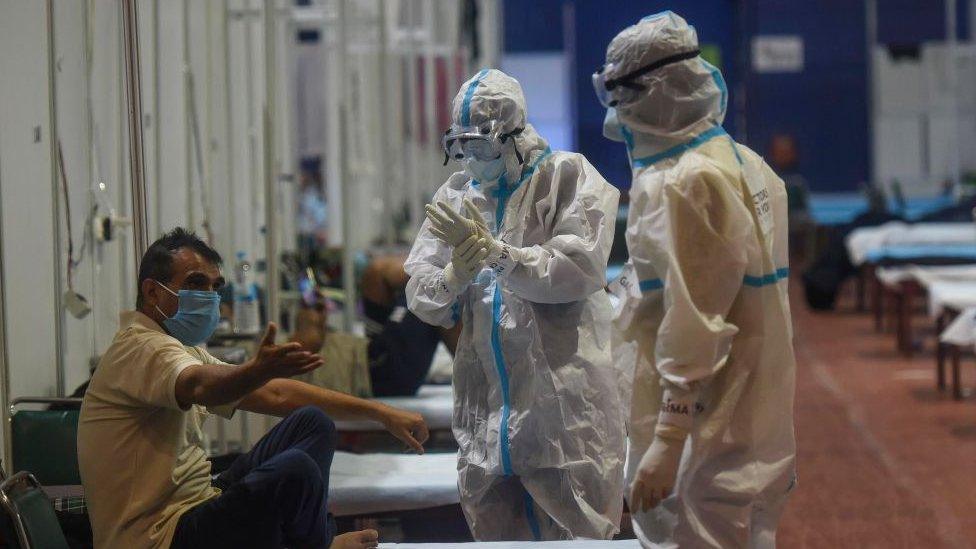 A Covid-19 patient talks to health workers wearing PPE kits inside a ward at the Commonwealth Games (CWG) Village Covid-19 care centre, near Pandav Nagar, on September 13, 2020 in New Delhi, India