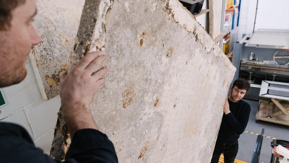 Two men carrying a Biohm insulation panel made from mycelium