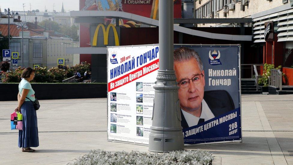 A woman looks at the United Russia political party's campaign poster promoting candidate Nikolai Gonchar in central Moscow