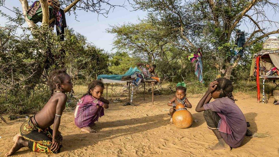 Children play in the sand as their mother wakes up.