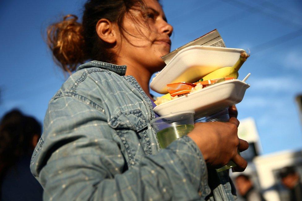 A migrant carries her food outside a temporary shelter in Tijuana, Mexico, 23 November