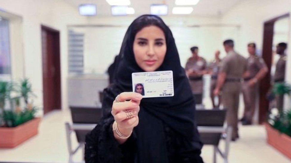 A woman holds out her new driving licence to the camera