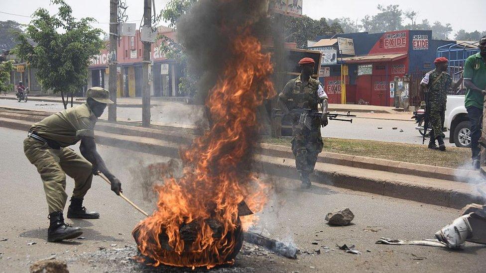 Uganda's military police intervenes near a burning barricade on February 19, 2016 in Kampala.