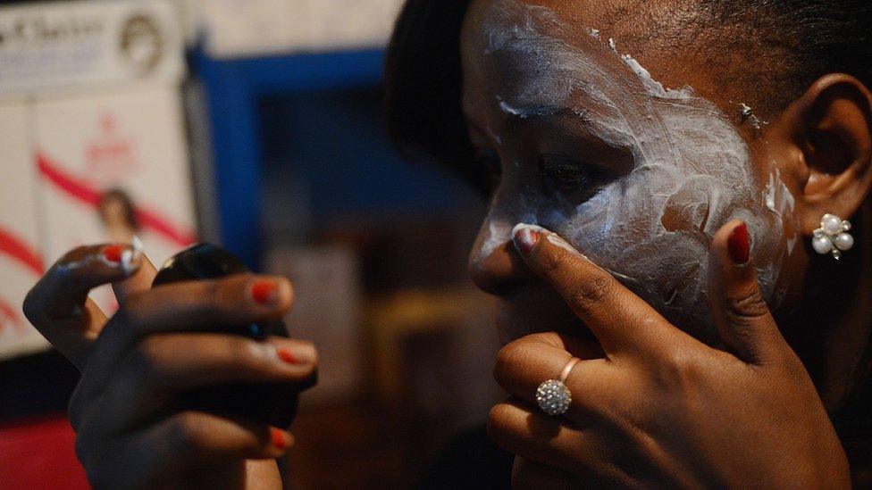 A beautician in Nairobi, Kenya shows how to rub skin-lightening cream, on March 18, 2015.