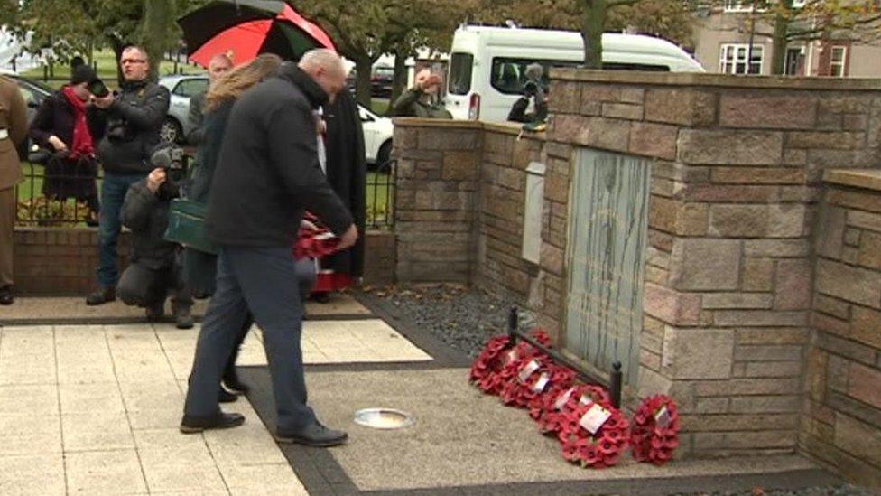 The stone and people laying wreaths there