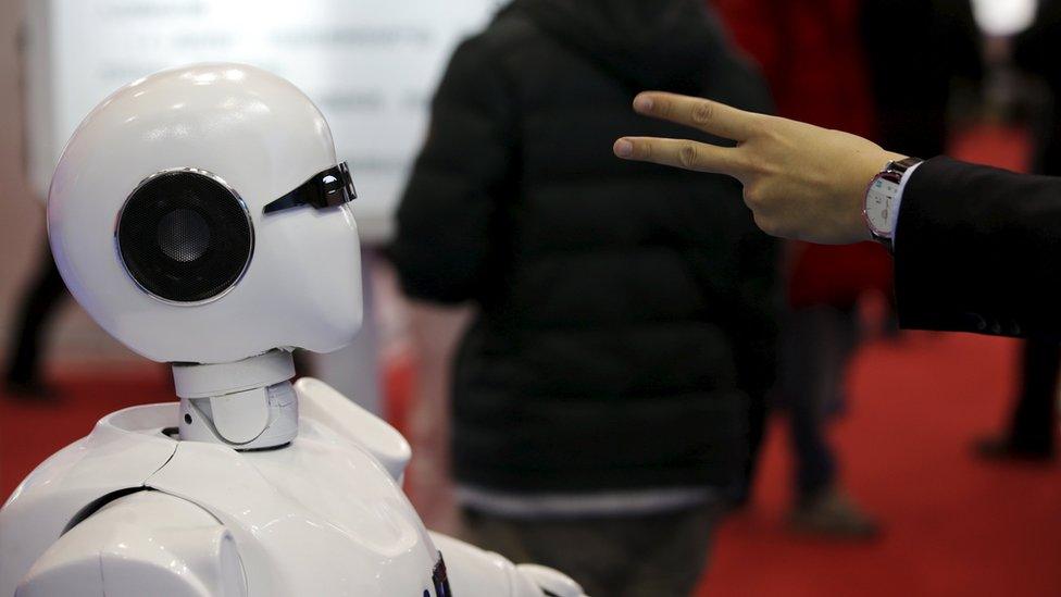 A visitor plays "rock, paper, scissors" at the World Robot Exhibition during the World Robot Conference