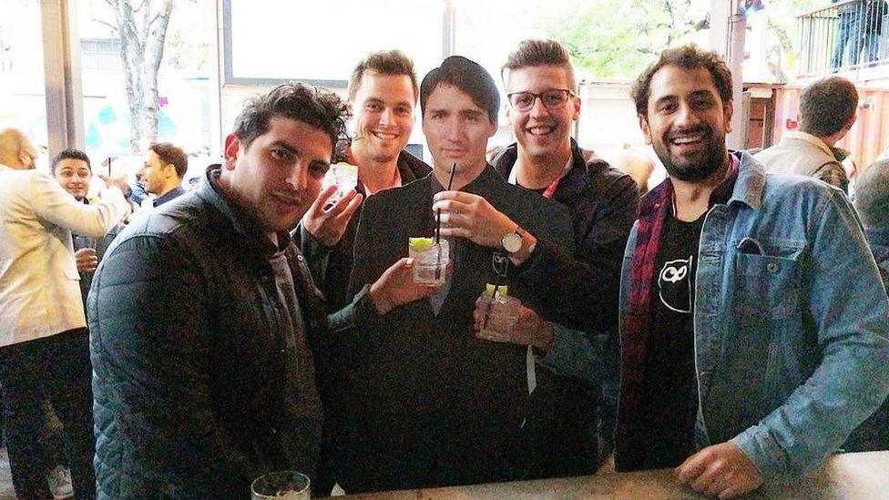 Four men posing with the cardboard cut out of Justin Trudeau in Austin