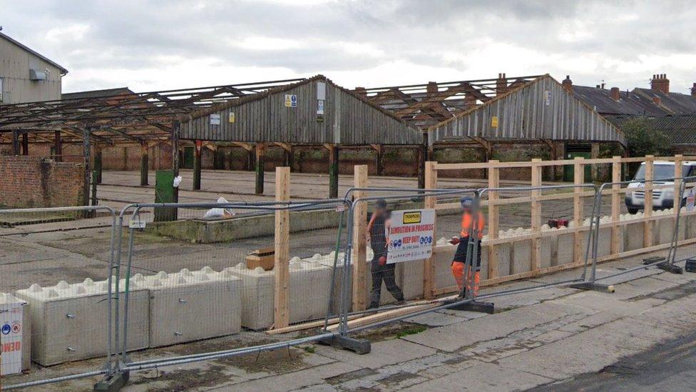 Workmen clear cattle market buildings