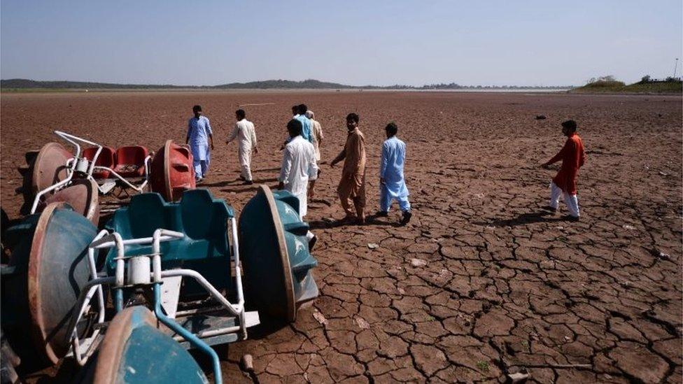 In this picture taken on June 19, 2018, Pakistani residents walk over a dried portion of the Rawal dam in Islamabad.