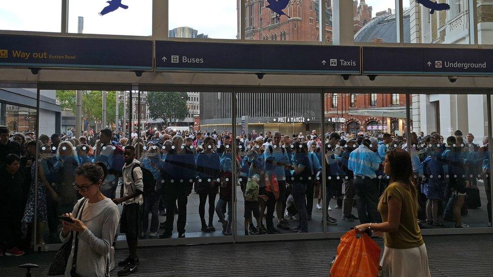 People waiting outside of King's Cross station, London, as all services in and out of the station have been suspended