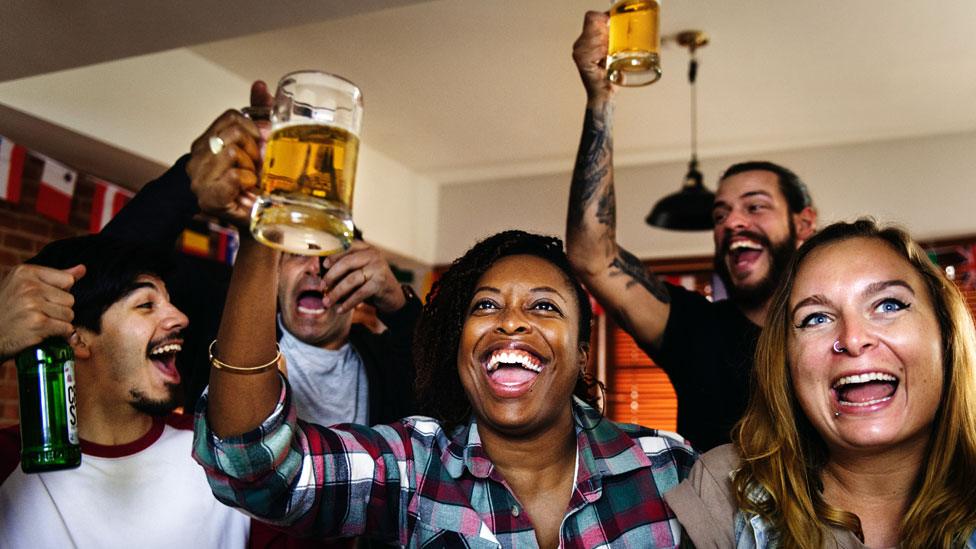 Men and women raise beer glasses