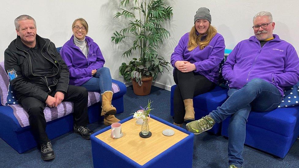 Two men and two women sit on sofas