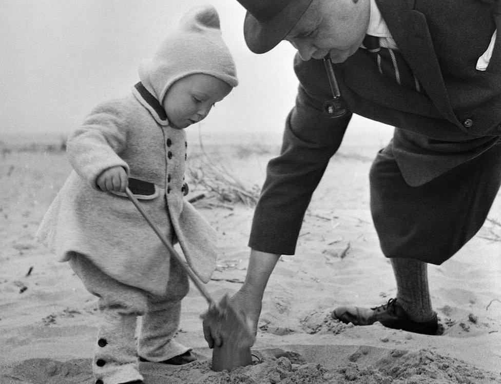 man helps child build sandcastle