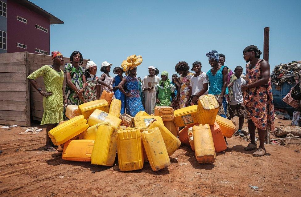 Men dressed in drag pictured near yellow jerrycans in Accra, Ghana