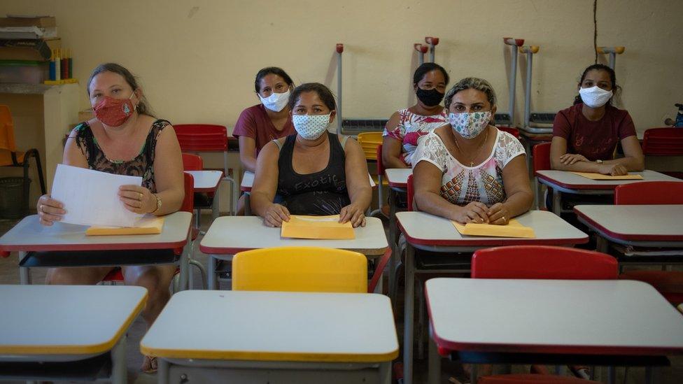 Mothers wait to pick up envelopes with their children's names on