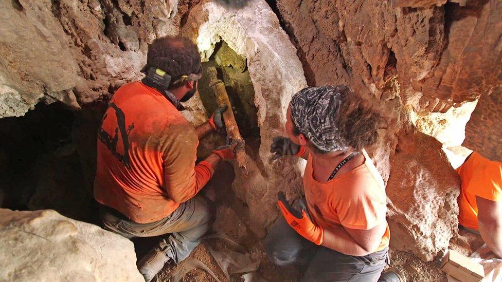 Removing the swords from the crevice where they were hidden. Photography Emil Aladjem Israel Antiquities Authority