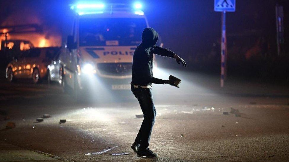 A protester throws a stone after a large number of cars were set on fire on Ramels vag in Rosengard