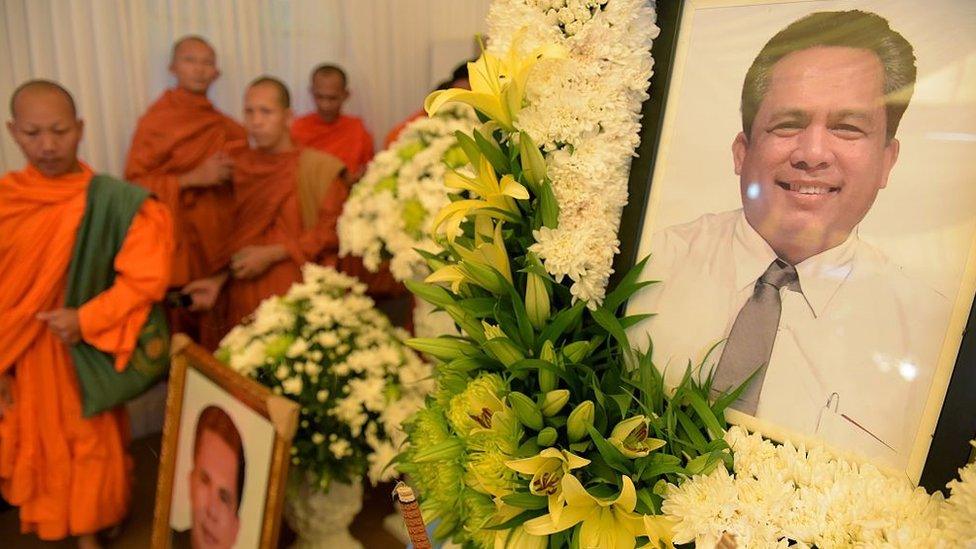 Cambodian Buddhist monks walk past portraits of Kem Ley, a political analyst and pro-democracy campaigner, during a funeral ceremony in Phnom Penh