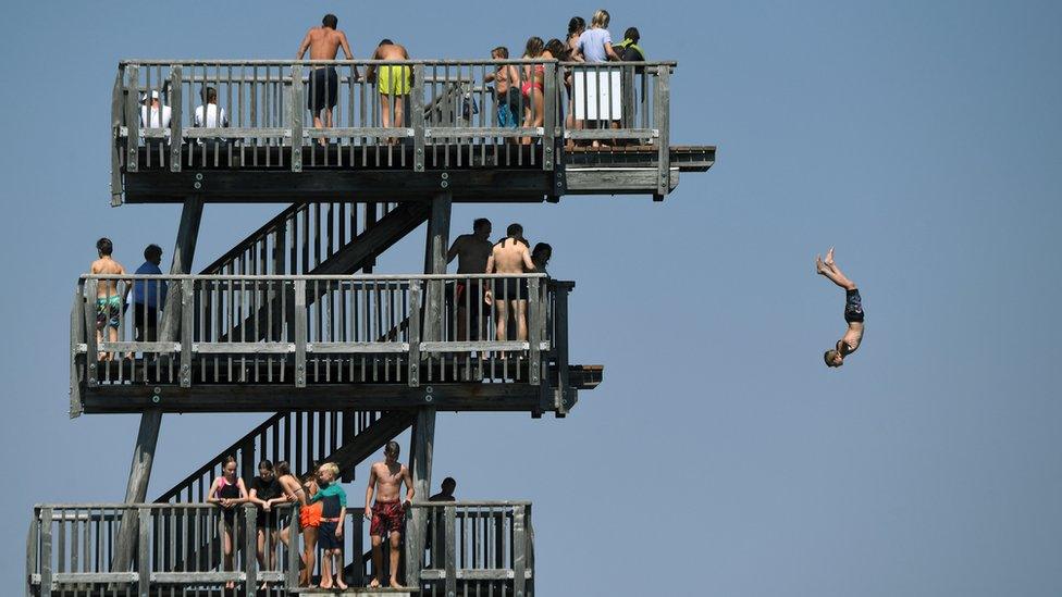 People line up to jump off a diving tower on the shore of the lake Ammersee near the small Bavarian village of Utting, southern Germany