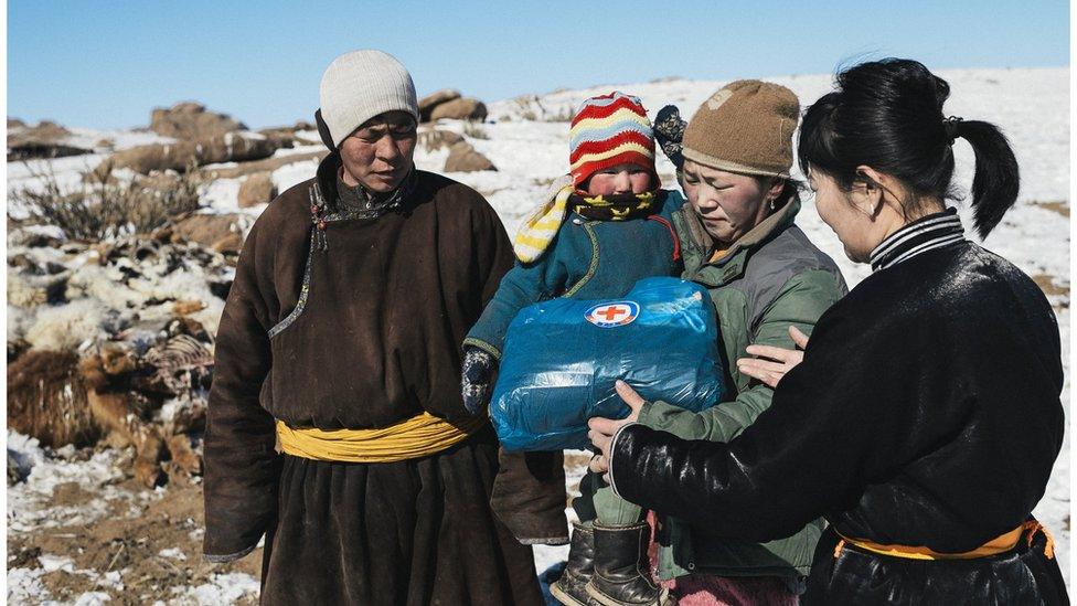 A family being given a Red Cross handout