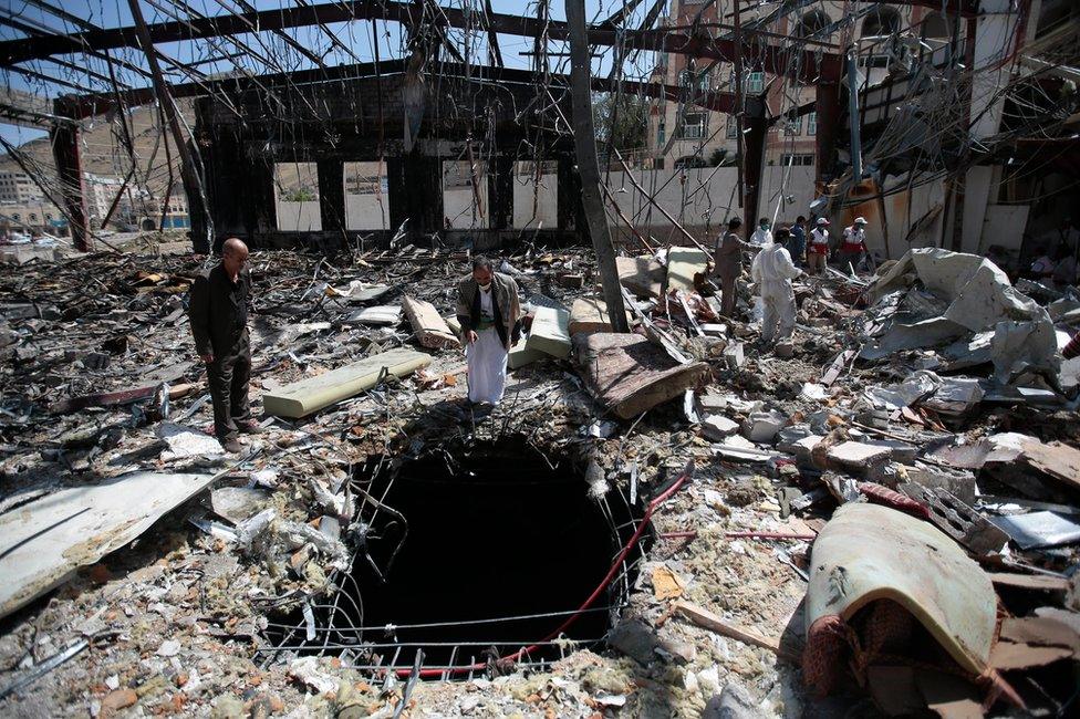 People inspect a funeral hall destroyed in a coalition air strike in Sanaa on 8 October