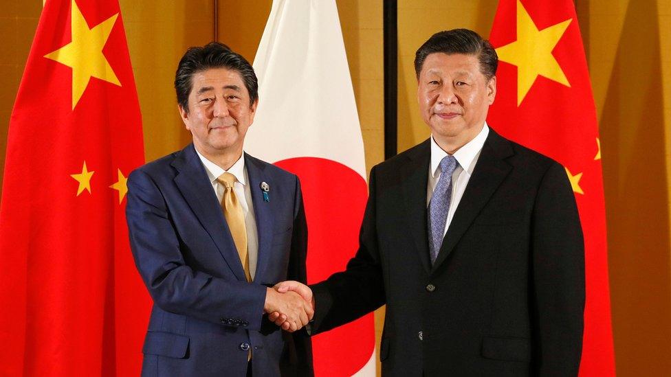 Japanese Prime Minister Shinzo Abe (R) shakes hands with Chinese President Xi Jinping