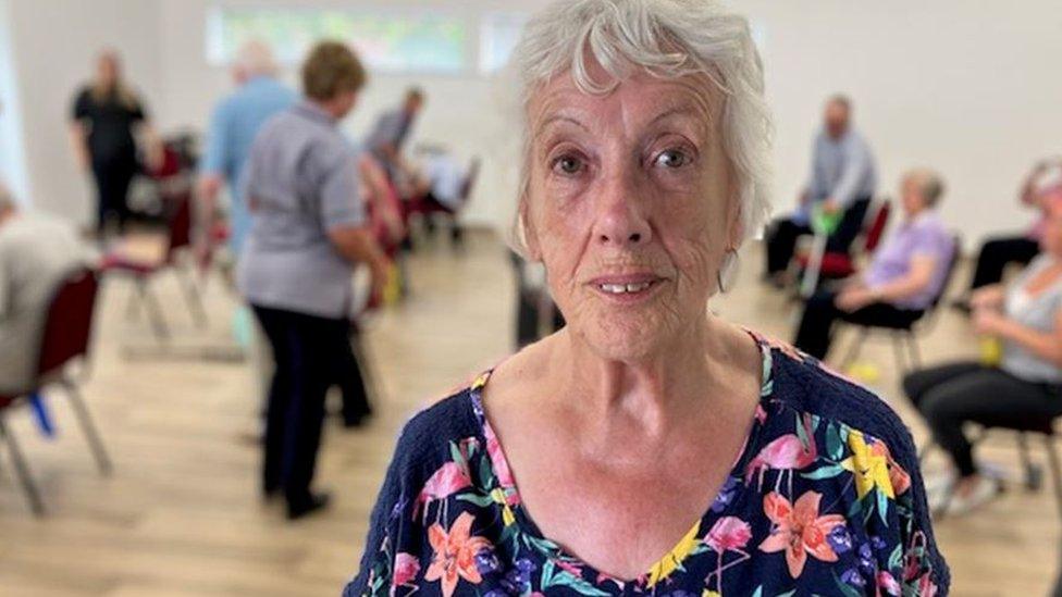 Pensioner Liz Hughes looks at the camera with a group of people in the background