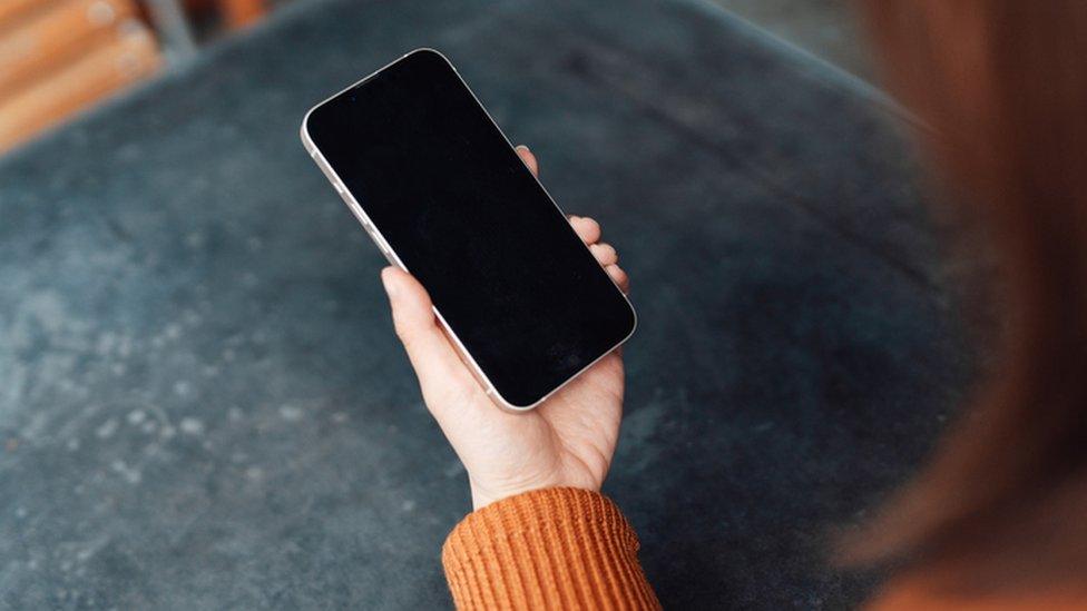 Over the shoulder view of young woman using smartphone - stock photo