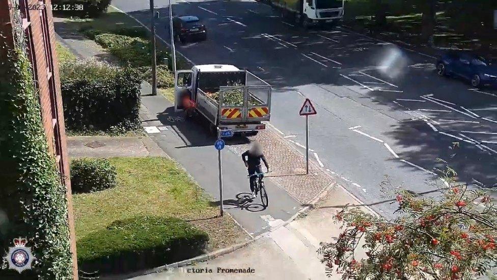 Cyclist riding on a cycle path with a road on one side and grass on the other