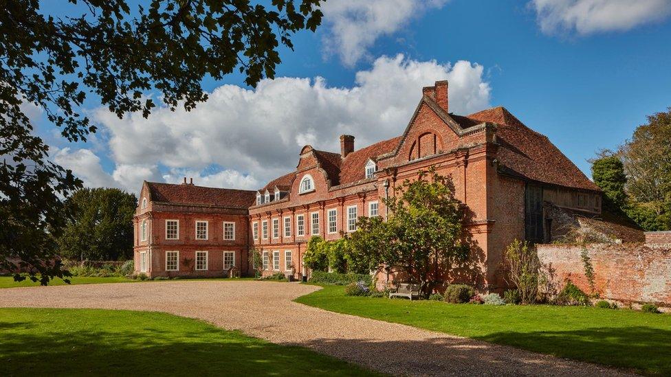 An external view of West Horsley Place, a red brick mansion with a long driveway