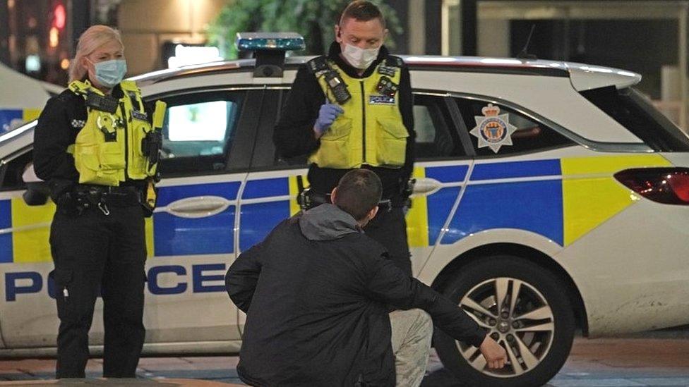 Police in masks speak to a member of the public in Newcastle