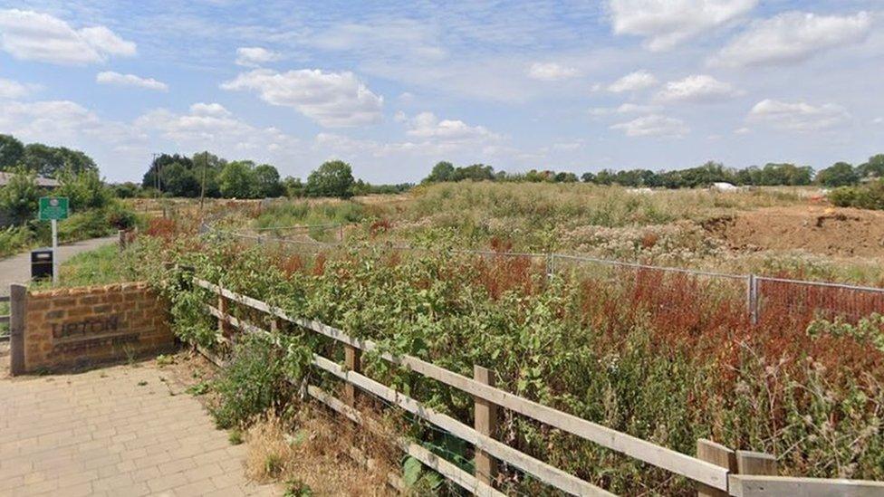 Wild grassland with wooden fence and "Upton Country Park" sign