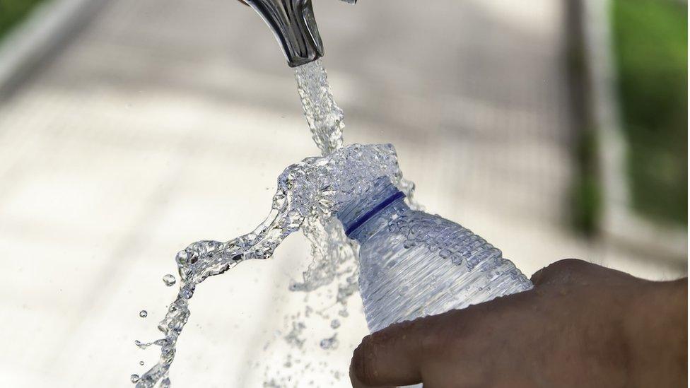 a person filling a bottle of water