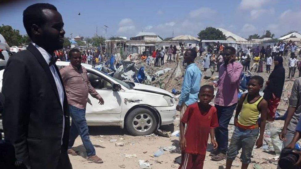 A photo showing the aftermath of the blast, with people standing in front of rubble