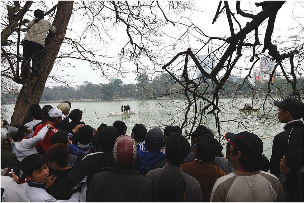 Hundreds of residents and tourists watch rescuers using boats and nets as they begin efforts to capture and treat a legendary but ailing giant turtle described as the 'spirit of the nation' at Hoan Kiem lake in the very heart of Hanoi on 8 March 2011.