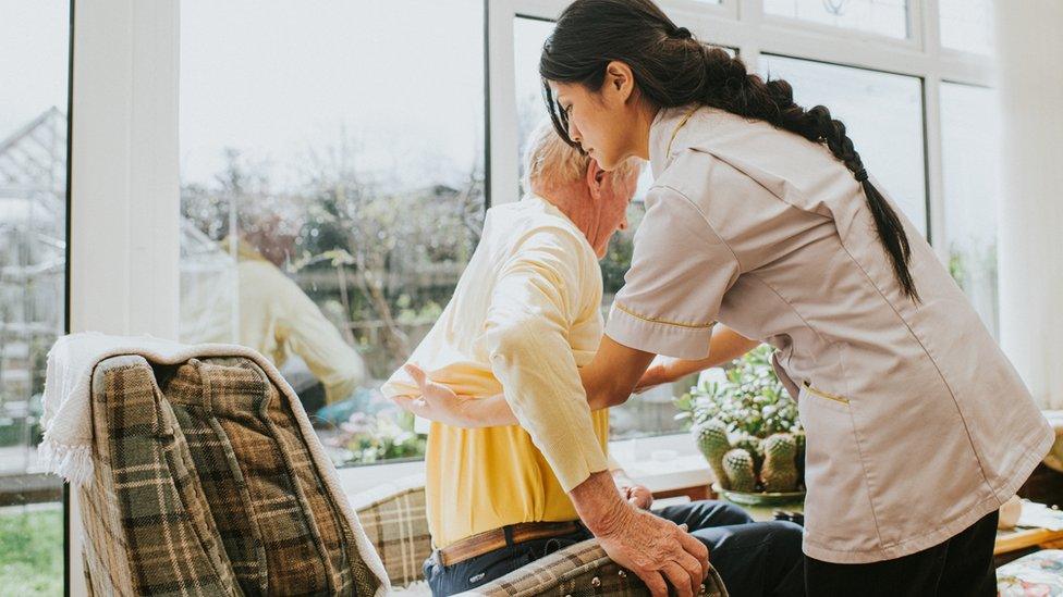 Young care assistant helps an elderly man