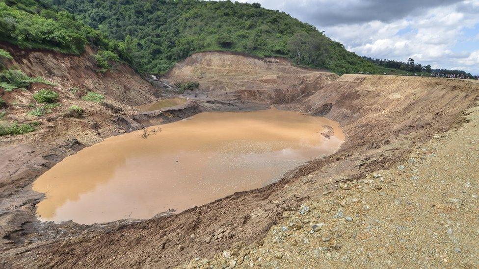 People stand overlooking the remains of Petal dam that burst its banks near the town of Solai, in Nakuru County on 10 May 2018.