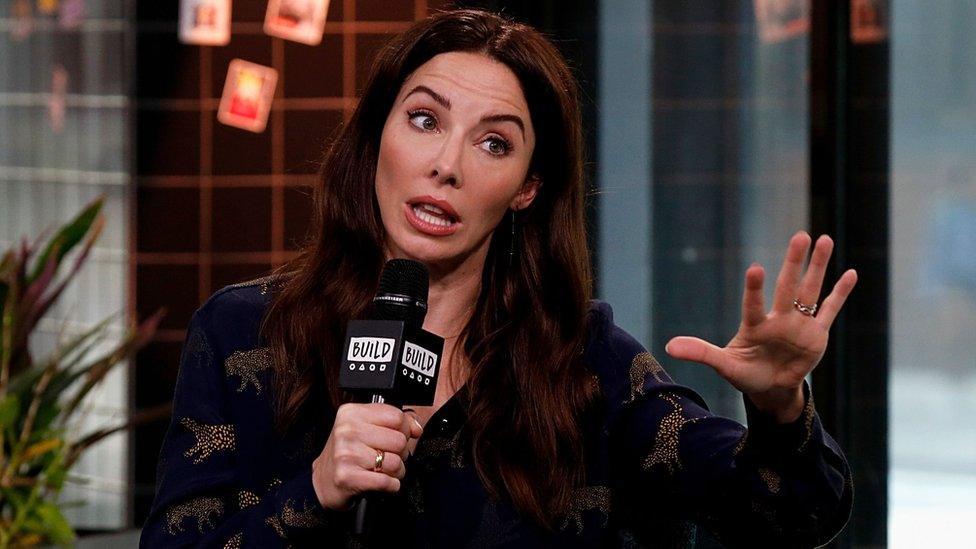 Whitney Cummings on a talk show, holding a microphone