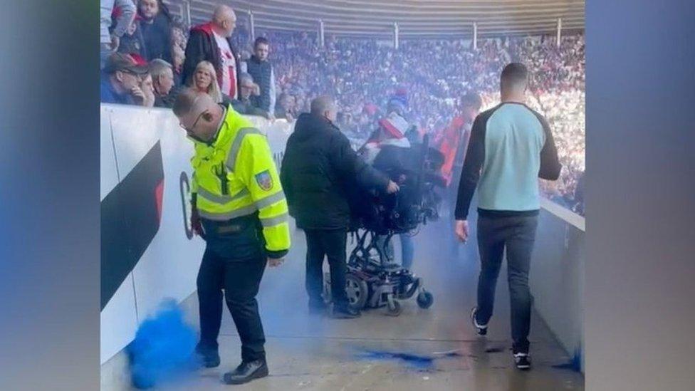 A plume of blue smoke rises into the air after a flare lands in the disabled fans' section at Sunderland's Stadium of Light