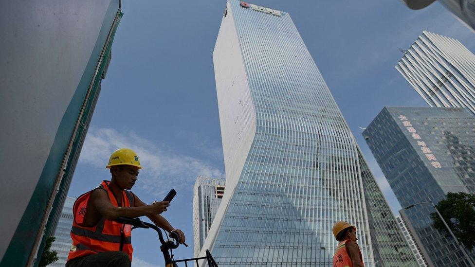 Workers walk in front of the Evergrande headquarters in Shenzhen, southeastern China on September 26, 2021.