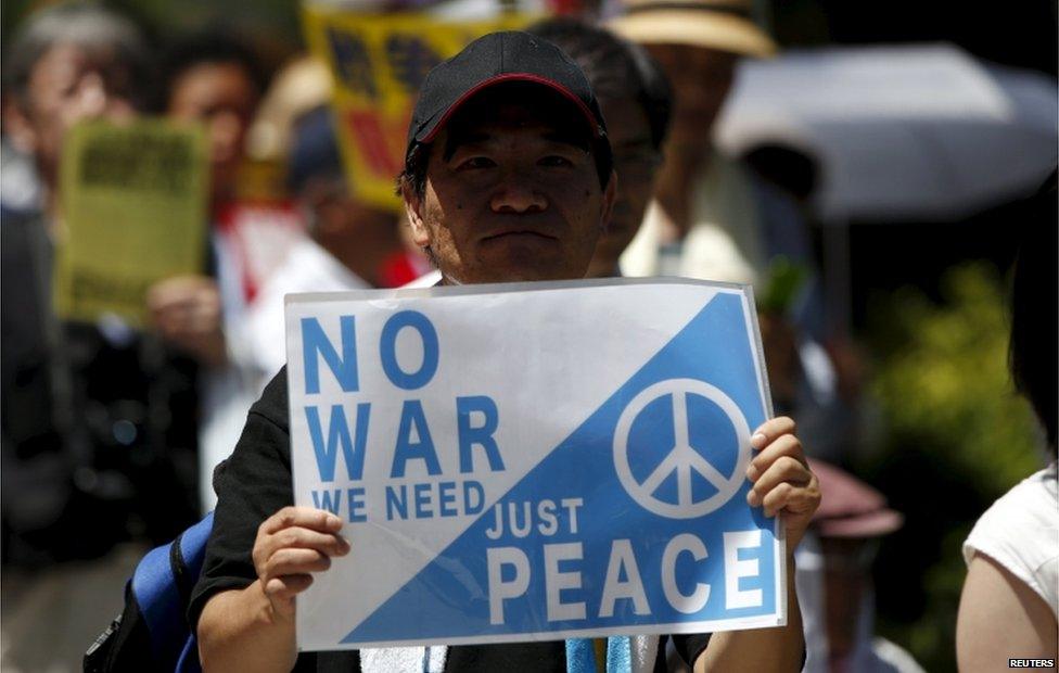 A protester holds a placard during a rally against Japan's Prime Minister Shinzo Abe"s administration and his security-related legislation in front of the parliament building in Tokyo 15 July, 2015.