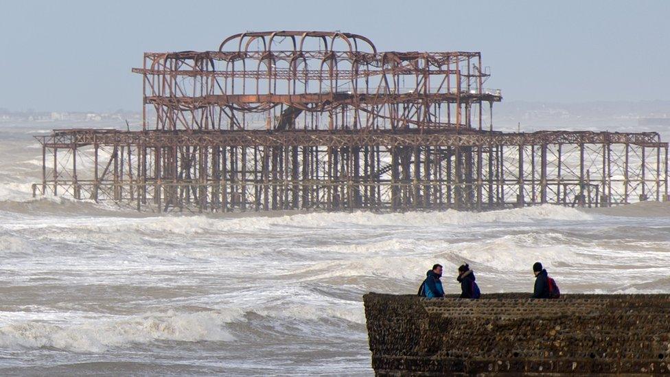 Tourists watch the waves on Brighton Beach